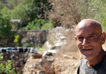 Eine männliche Person steht vor einem Olivenhain und blickt in die Kamera. Foto: Gerd Herzog