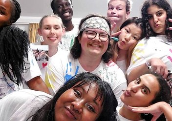 Acht junge Erwachsenen schauen mit auffälligen Posen oder Grimassen in die Kamera