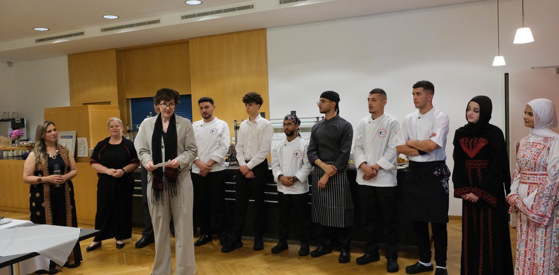 Stellvertretnde Direktorin Magdalena Stachura begrüßt die Gäste der Arabischen Nacht. Hinter ihr stehen die Berufsschüler:innen des Talitha Kumi Community College.