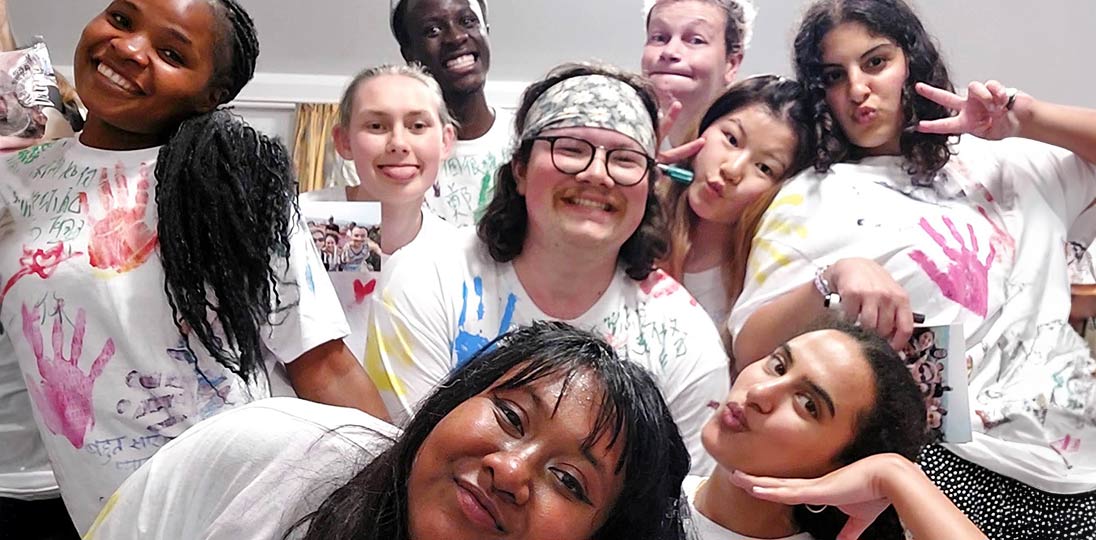 Acht junge Erwachsenen schauen mit auffälligen Posen oder Grimassen in die Kamera